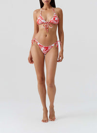 Woman wearing a red and white patterned bikini on a light gray background
